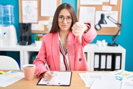 Photo for Young hispanic woman working at the office wearing glasses looking unhappy and angry showing rejection and negative with thumbs down gesture. bad expression. - Royalty Free Image