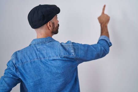 Photo for Hispanic man with beard standing over isolated background posing backwards pointing ahead with finger hand - Royalty Free Image