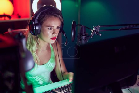 Photo for Young beautiful hispanic woman streamer playing video game using computer at gaming room - Royalty Free Image