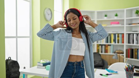 Foto de Estudiante afroamericana sonriendo confiada escuchando música en la universidad de la biblioteca - Imagen libre de derechos