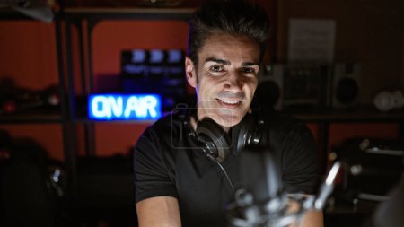 Foto de Joven reportero de radio hispano sonriendo confiado en estudio de radio - Imagen libre de derechos