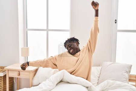 Photo for African american man waking up stretching arms at bedroom - Royalty Free Image