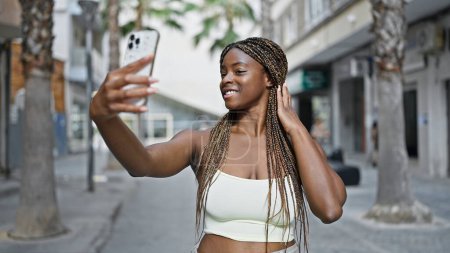 Foto de Mujer afroamericana hacer selfie por teléfono inteligente sonriendo en la calle - Imagen libre de derechos