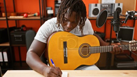 Foto de Músico afroamericano tocando guitarra clásica componiendo canción en estudio de música - Imagen libre de derechos