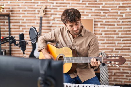 Foto de Young man musician playing classical guitar at music studio - Imagen libre de derechos