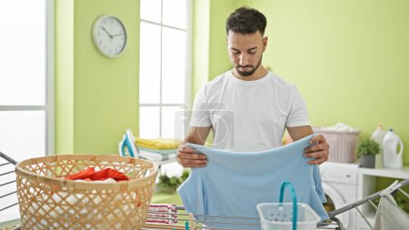 Foto de Hombre árabe joven colgando ropa en tendedero en la lavandería - Imagen libre de derechos