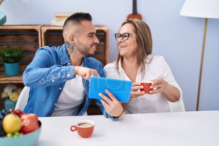 Photo for Man and woman mother and son drinking coffee using touchpad at home - Royalty Free Image