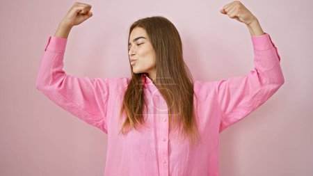 Photo for Vibrant young hispanic woman flaunts her beautiful confidence, powerfully gesturing with strong arms, radiating joy and positivity, smiling cheerfully against an isolated pink background. - Royalty Free Image