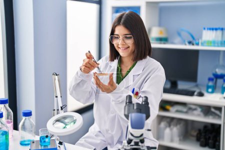 Photo for Young beautiful hispanic woman scientist smiling confident holding sample at laboratory - Royalty Free Image
