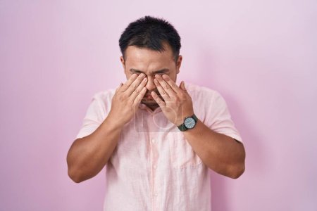Téléchargez les photos : Jeune homme chinois debout sur fond rose frottant les yeux pour la fatigue et les maux de tête, somnolent et l'expression fatiguée. problème de vision - en image libre de droit