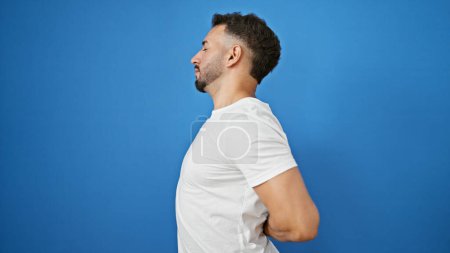 Téléchargez les photos : Jeune homme arabe souffrant de maux de dos sur fond bleu isolé - en image libre de droit