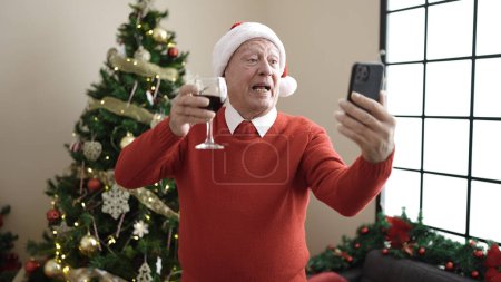 Téléchargez les photos : Senior boire du vin faire appel vidéo à la maison - en image libre de droit
