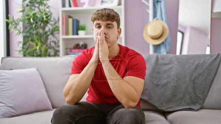 Photo for Young hispanic man stressed sitting on sofa at home - Royalty Free Image