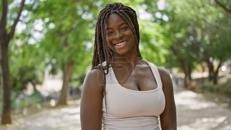 Foto de Mujer afroamericana sonriendo confiada de pie en el parque - Imagen libre de derechos