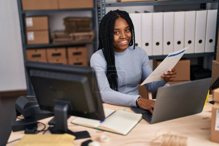 Téléchargez les photos : Africaine américaine femme commerce électronique travailleur d'affaires en utilisant un ordinateur portable document de lecture au bureau - en image libre de droit