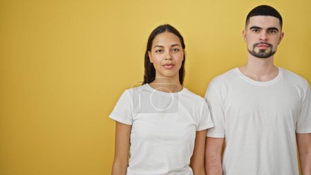 Photo for Beautiful couple standing together with serious face over isolated yellow background - Royalty Free Image