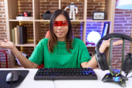 Téléchargez les photos : Femme chinoise du Moyen Âge portant des lunettes de réalité virtuelle expression désemparée et confuse avec les bras et les mains levées. concept de doute. - en image libre de droit