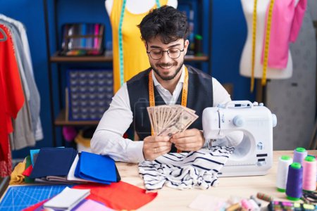 Photo for Young hispanic man tailor smiling confident holding dollars at sewing studio - Royalty Free Image