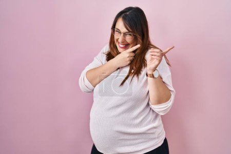 Photo for Pregnant woman standing over pink background pointing aside worried and nervous with both hands, concerned and surprised expression - Royalty Free Image