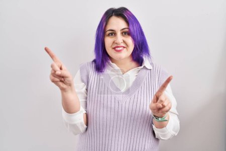 Téléchargez les photos : Plus taille femme avec les cheveux violets debout sur fond blanc souriant confiant pointant avec les doigts vers différentes directions. espace de copie pour la publicité - en image libre de droit