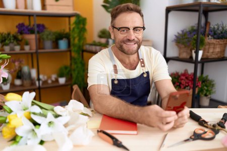 Photo for Middle age man florist smiling confident using smartphone at flower shop - Royalty Free Image