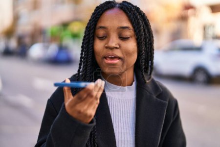 Téléchargez les photos : African american woman talking on smartphone with serious expression at street - en image libre de droit