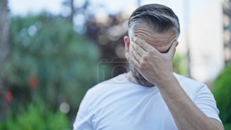 Téléchargez les photos : Homme aux cheveux gris souffrant de maux de tête au parc - en image libre de droit