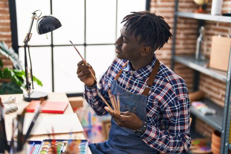 Foto de Hombre afroamericano artista sosteniendo pinceles en el estudio de arte - Imagen libre de derechos