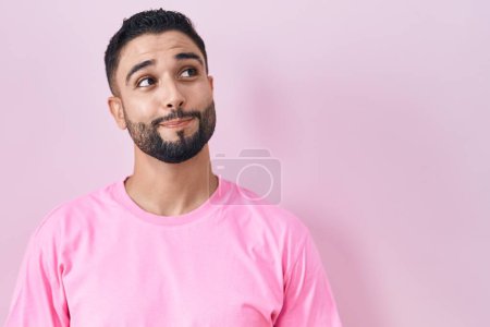 Photo for Hispanic young man standing over pink background smiling looking to the side and staring away thinking. - Royalty Free Image
