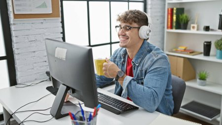 Photo for Young hispanic man working at the office, portrait of a professional in a power breakfast, drinking coffee, using computer, wearing headphones, and having video calls on the internet - Royalty Free Image