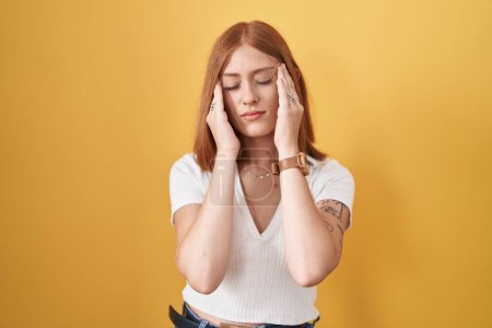 Photo for Young redhead woman standing over yellow background with hand on head, headache because stress. suffering migraine. - Royalty Free Image