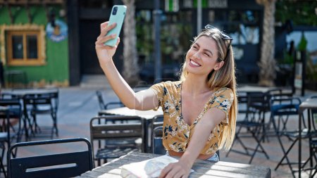 Téléchargez les photos : Jeune femme blonde touriste souriant confiant faire selfie par smartphone à la terrasse du café - en image libre de droit