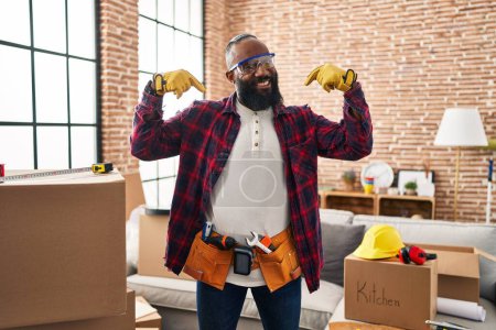 Photo for African american man working at home renovation looking confident with smile on face, pointing oneself with fingers proud and happy. - Royalty Free Image