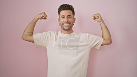 Photo for Radiant young hispanic man exudes confidence, his arms gesturing strong sign, smiling joyfully over isolated pink background. an epitome of positivity, this handsome guy simply enjoys being. - Royalty Free Image