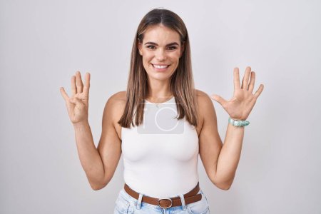 Photo for Hispanic young woman standing over white background showing and pointing up with fingers number nine while smiling confident and happy. - Royalty Free Image