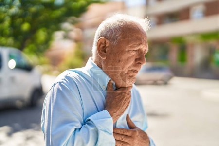 Téléchargez les photos : Homme âgé aux cheveux gris souffrant d'une crise cardiaque dans la rue - en image libre de droit