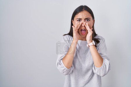 Téléchargez les photos : Young hispanic woman standing over white background shouting angry out loud with hands over mouth - en image libre de droit