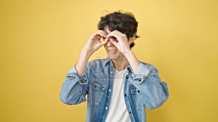 Photo for Young hispanic man smiling confident doing binoculars gesture with hands over isolated yellow background - Royalty Free Image