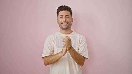 Foto de Joven hombre hispano sonriendo confiado aplaudiendo sobre aislado fondo rosa - Imagen libre de derechos