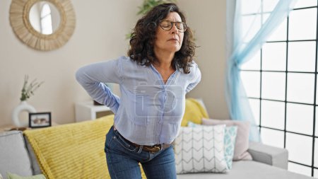 Photo for Middle age hispanic woman suffering for backache sitting on sofa at home - Royalty Free Image