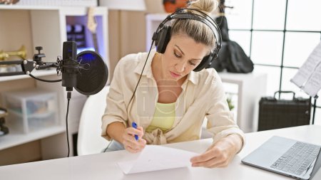 Photo for Young blonde woman musician composing song at music studio - Royalty Free Image