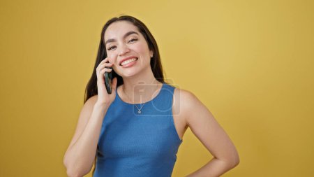 Téléchargez les photos : Jeune belle femme hispanique souriant confiant parler sur le smartphone sur fond jaune isolé - en image libre de droit