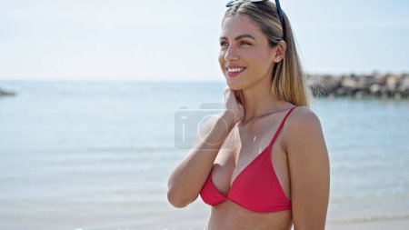 Téléchargez les photos : Jeune femme blonde touriste souriant confiant portant un bikini à la plage - en image libre de droit