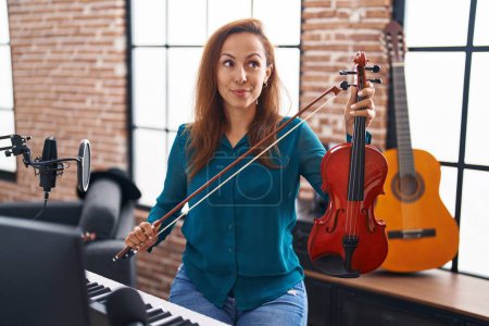 Photo for Brunette woman playing violin smiling looking to the side and staring away thinking. - Royalty Free Image