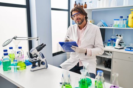 Photo for Middle age man scientist smiling confident writing on document at laboratory - Royalty Free Image