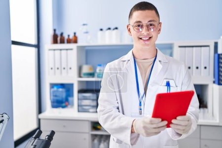 Photo for Young hispanic man scientist smiling confident using touchpad at laboratory - Royalty Free Image
