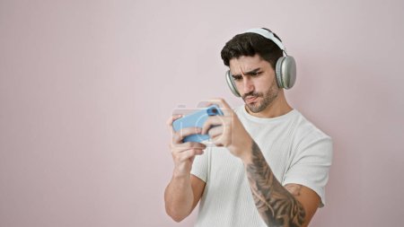 Photo for Young hispanic man playing video game over isolated pink background - Royalty Free Image