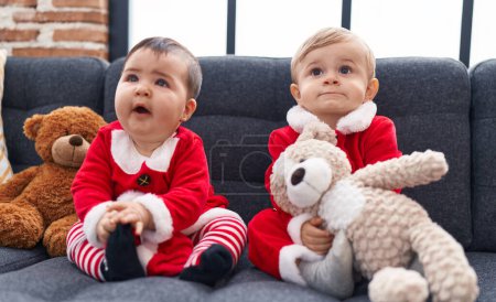 Photo for Adorable boy and girl wearing christmas clothes holding teddy bear at home - Royalty Free Image