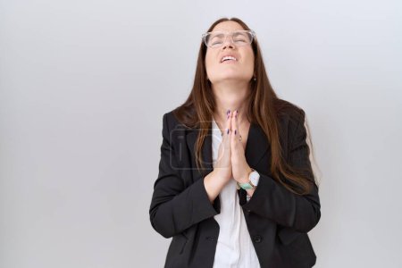 Photo for Beautiful brunette woman wearing business jacket and glasses begging and praying with hands together with hope expression on face very emotional and worried. begging. - Royalty Free Image