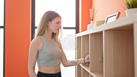Téléchargez les photos : Jeune femme blonde organisant étagères à la maison - en image libre de droit